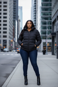 Black puffer jacket styled with dark jeans and ankle boots on city street