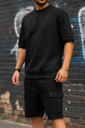Man wearing black oversized tee and cargo shorts matching set